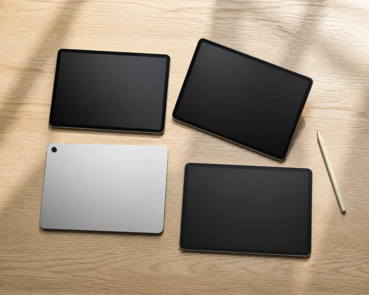 Tablets and a stylus laid out on a wooden desk